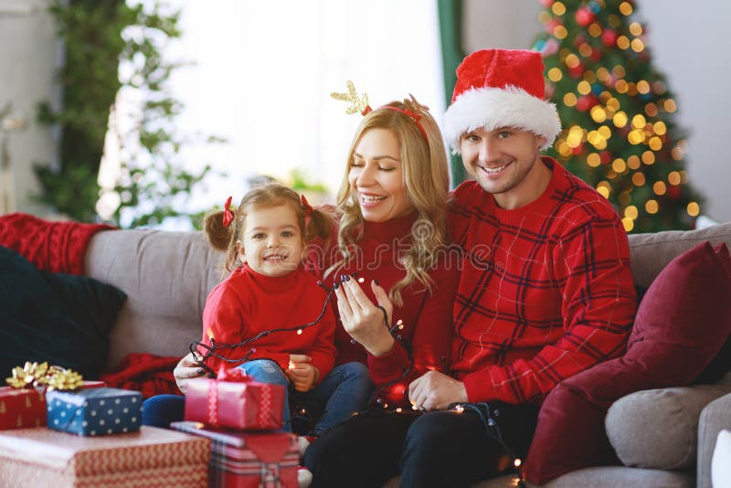 Genitori felici della famiglia e presente aperti della figlia del bambino sulla mattina di natale immagine stock Genitori felici della famiglia e presente aperti della figlia del bambino sulla mattina di natale immagine stock