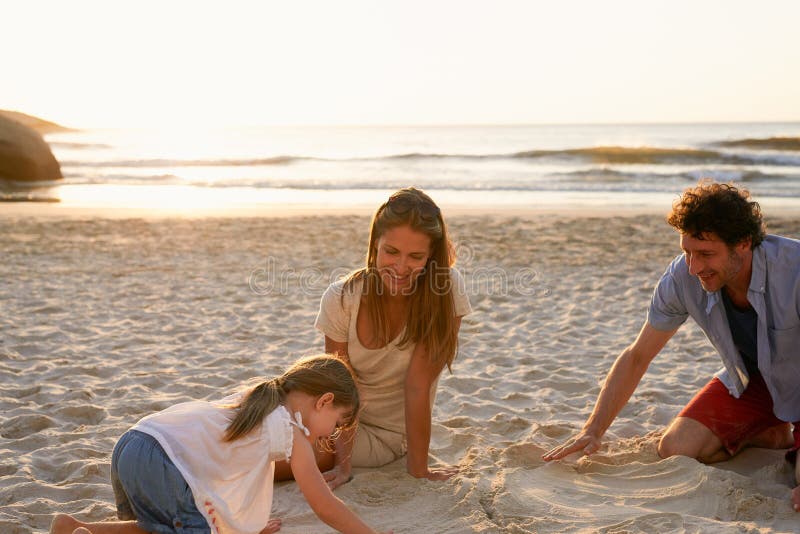 Genitori, ragazza e figlio in spiaggia con castello di sabbia giocherellato e legato con sorriso, amore ed outdoor in vacanza. pad fotografia stock libera da diritti