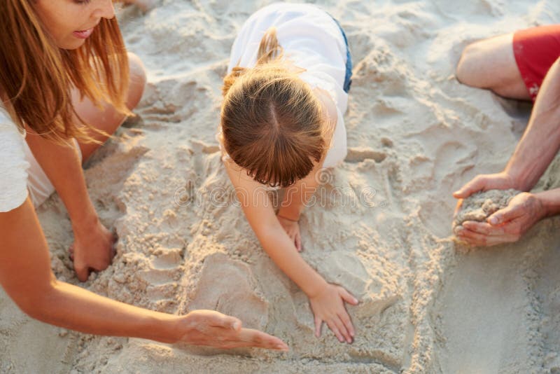 Genitori ragazze e bambini in spiaggia con sandCastle giocoso e legato all'amore familiare e sopra in vacanza. padre immagine stock libera da diritti