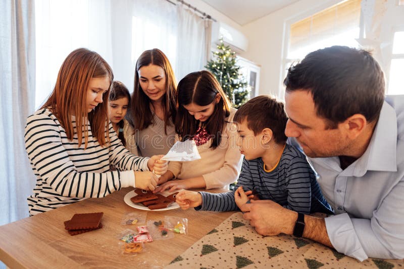 Genitori sorridenti e bambini cucinano insieme i biscotti natalizi in cucina fotografia stock libera da diritti