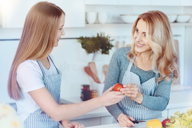 Genitrice amorosa e ragazza che sorridono mentre producendo insalata insieme fotografia stock libera da diritti Genitrice amorosa e ragazza che sorridono mentre producendo insalata insieme fotografia stock libera da diritti
