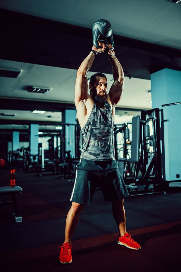 Genomkörare för man för övning för konditionKettlebells gunga på idrottshallen. Övningen för konditionKettlebells gunga uppsökte mangenomkörare på idrottshallen