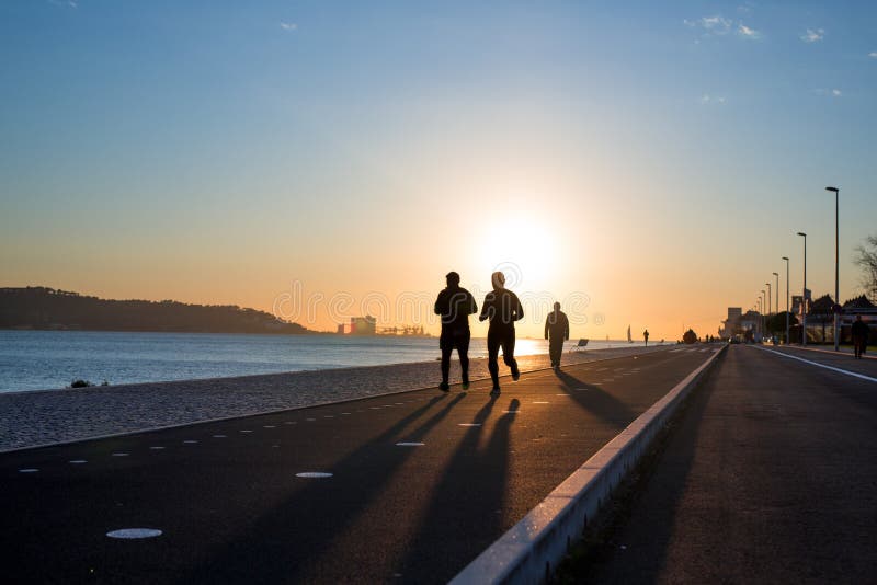 Genomkörarebakgrund, två personer som joggar på stranden på solnedgången, löparekonturer, sunt livsstilbegrepp royaltyfri foto Genomkörarebakgrund, två personer som joggar på stranden på solnedgången, löparekonturer, sunt livsstilbegrepp royaltyfri foto