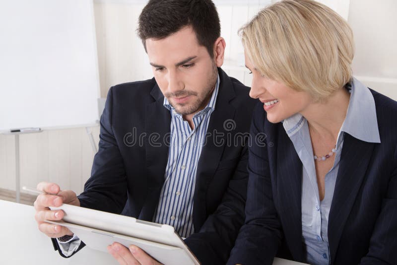 Gens d'affaires masculins et féminins regardant un écran d'un comprimé photographie stock Gens d'affaires masculins et féminins regardant un écran d'un comprimé photographie stock