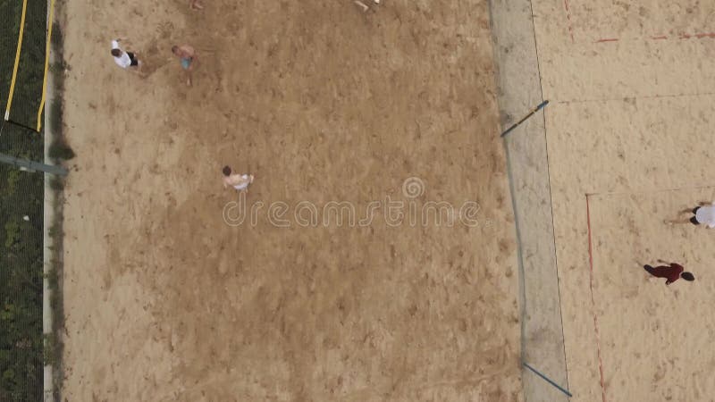 Gente aerea del colpo che gioca calcio della spiaggia su due settori coperti di sabbia