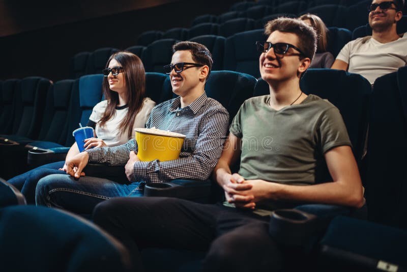 Gente con película de observación de las palomitas en cine imagen de archivo libre de regalías Gente con película de observación de las palomitas en cine imagen de archivo libre de regalías