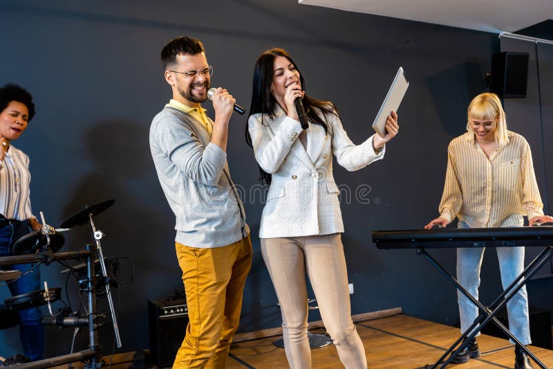 Gente de negocios haciendo ejercicio de entrenamiento de equipo durante el seminario de formación de equipos cantando karaoke imagen de archivo