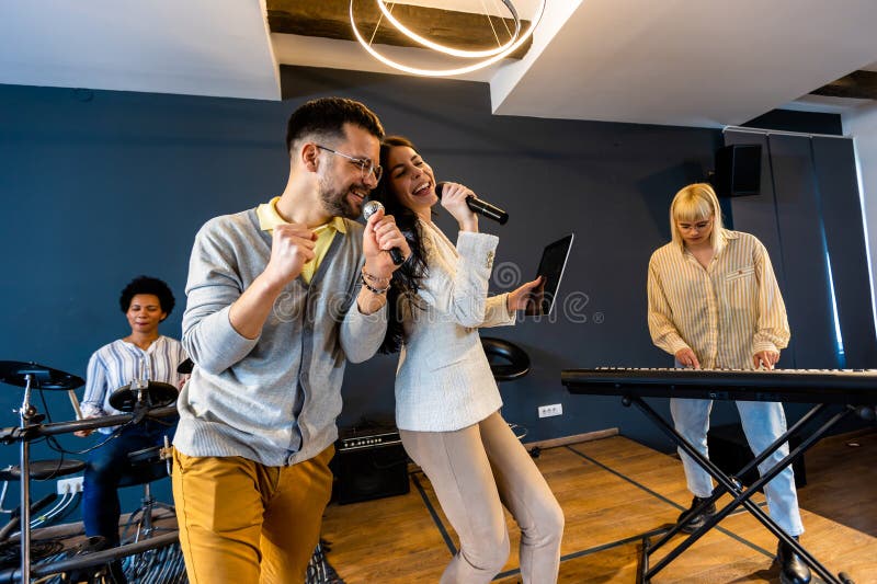 Gente de negocios haciendo ejercicio de entrenamiento de equipo durante el seminario de formación de equipos cantando karaoke imagen de archivo