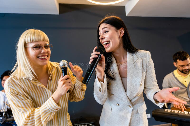 Gente de negocios haciendo ejercicio de entrenamiento de equipo durante el seminario de formación de equipos cantando karaoke imagenes de archivo