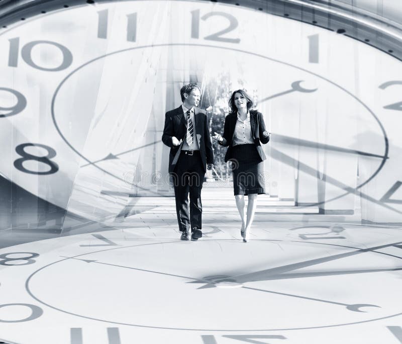 Gente di affari che cammina su un fondo dell'orologio fotografia stock libera da diritti Gente di affari che cammina su un fondo dell'orologio fotografia stock libera da diritti