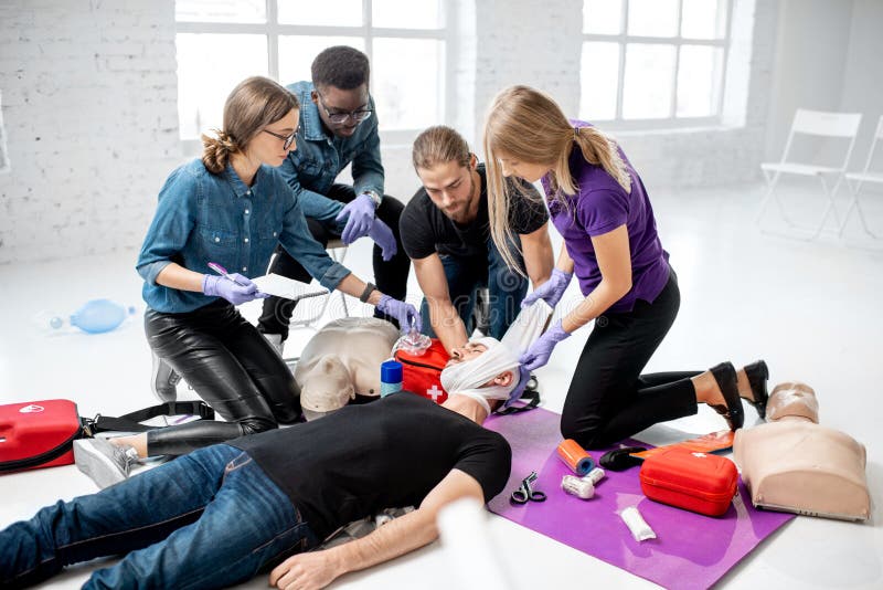 Group of young people during the first aid training with instructor showing how to apply a bandage on injured person. Group of young people during the first aid training with instructor showing how to apply a bandage on injured person