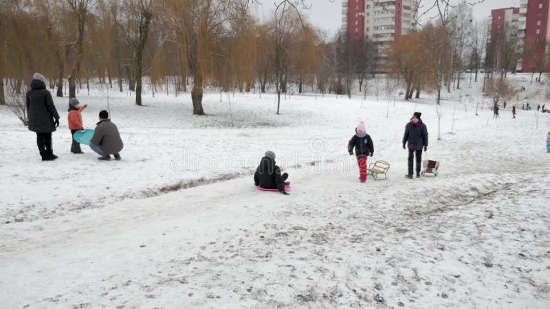 Gente durmiendo en una colina de nieve en el patio de un edificio de varios pisos. niños corriendo por la diapositiva : gomel bela