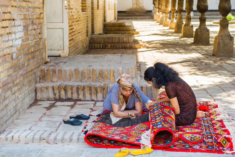 KHIVA, UZBEKISTAN - JUNE 4, 2011: Two unidentified Uzbek women are working on a carpet in Uzbekistan, Jun 4, 2011. 81% of people in Uzbekistan belong to Uzbek ethnic group. KHIVA, UZBEKISTAN - JUNE 4, 2011: Two unidentified Uzbek women are working on a carpet in Uzbekistan, Jun 4, 2011. 81% of people in Uzbekistan belong to Uzbek ethnic group