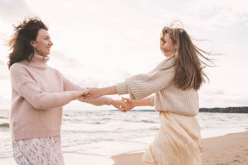 Gente feliz baila cerca del mar. dos novias cogiendo la mano. las hermanas tienen una relación muy estrecha. el derecho a imágenes de archivo libres de regalías