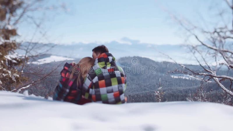 Gente joven en desgaste elegante del invierno Muchacho joven hermoso que besa a su novia preciosa en frente mientras que se sient