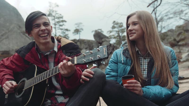 Gente joven preciosa que canta junto una canción, riendo feliz durante la comida campestre en el parque del otoño Memorias felice