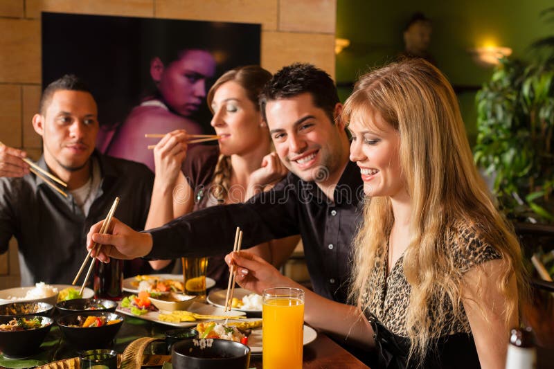 Gente joven que come en restaurante tailandés foto de archivo libre de regalías Gente joven que come en restaurante tailandés foto de archivo libre de regalías