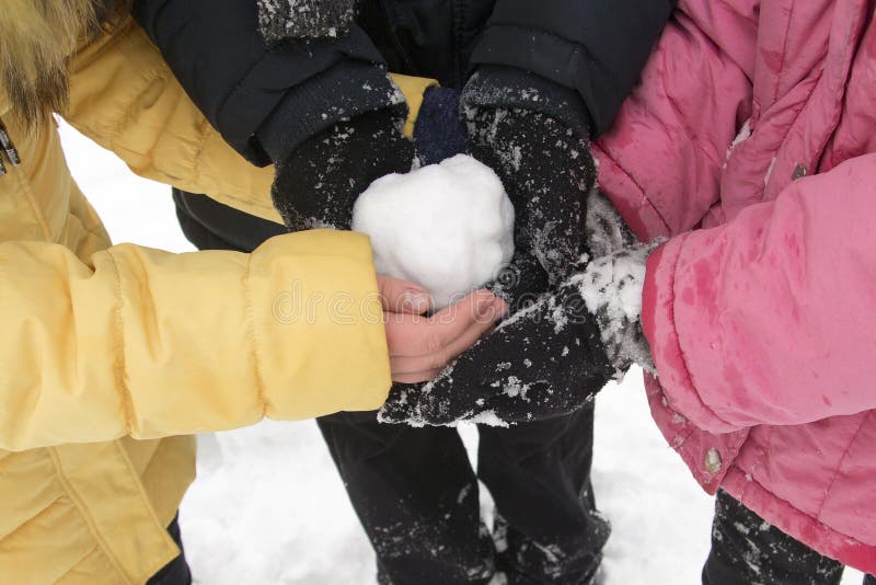Gente joven que sostiene una bola de nieve en sus manos en el parque del invierno fotos de archivo Gente joven que sostiene una bola de nieve en sus manos en el parque del invierno fotos de archivo