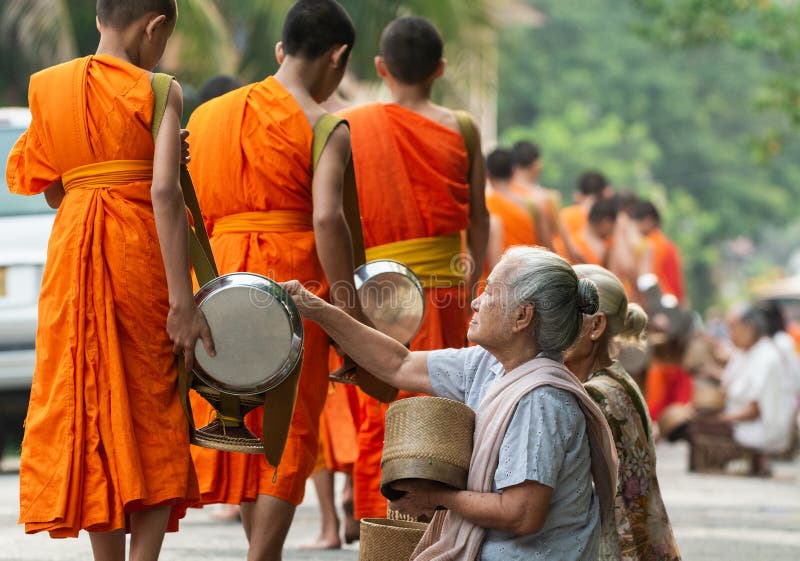 Gente laosiana que hace ofrendas a los monjes budistas durante las limosnas tradicionales que dan ceremonia en la ciudad de Luang foto de archivo Gente laosiana que hace ofrendas a los monjes budistas durante las limosnas tradicionales que dan ceremonia en la ciudad de Luang foto de archivo