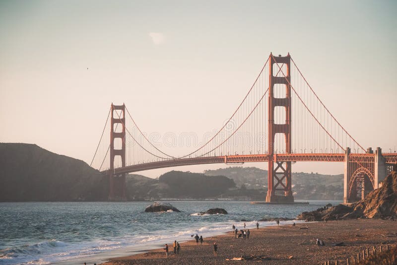 Gente que camina cerca de una playa en un día suuny con puente Golden Gate en el fondo imagen de archivo Gente que camina cerca de una playa en un día suuny con puente Golden Gate en el fondo imagen de archivo