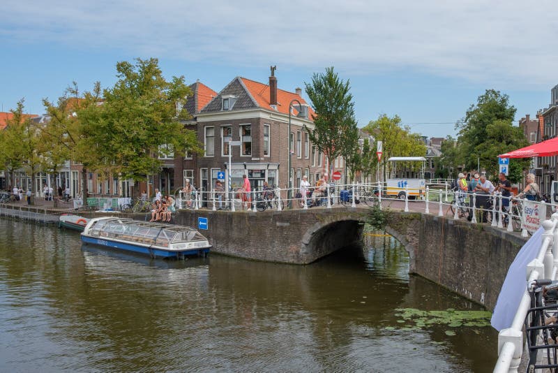 Gente que mira el canal viejo histórico hermoso en el centro de la cerámica de Delft, Países Bajos foto de archivo Gente que mira el canal viejo histórico hermoso en el centro de la cerámica de Delft, Países Bajos foto de archivo