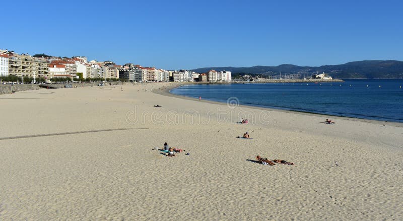 Gente que toma el sol en la playa Arena brillante y mar azul Día soleado, cielo claro Sanxenxo, Galicia, España imágenes de archivo libres de regalías Gente que toma el sol en la playa Arena brillante y mar azul Día soleado, cielo claro Sanxenxo, Galicia, España imágenes de archivo libres de regalías