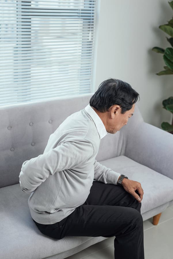 Gente, salud y concepto de problemas - anciano infeliz que sufre de dolor en la espalda o en las riendas en casa imagen de archivo Gente, salud y concepto de problemas - anciano infeliz que sufre de dolor en la espalda o en las riendas en casa imagen de archivo
