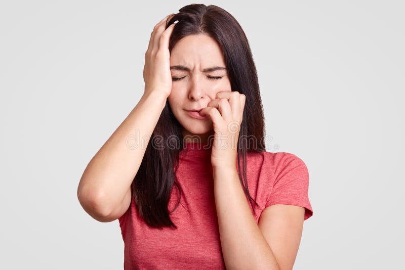 Gente y concepto de la tristeza La hembra morena subrayada mantiene ojos cerrados, toca la cabeza, siente dolor, estando en pánic foto de archivo Gente y concepto de la tristeza La hembra morena subrayada mantiene ojos cerrados, toca la cabeza, siente dolor, estando en pánic foto de archivo