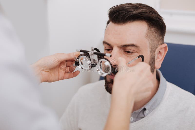 Gentil docteur féminin donnant des verres d'essai d'oeil à son patient images stock Gentil docteur féminin donnant des verres d'essai d'oeil à son patient images stock