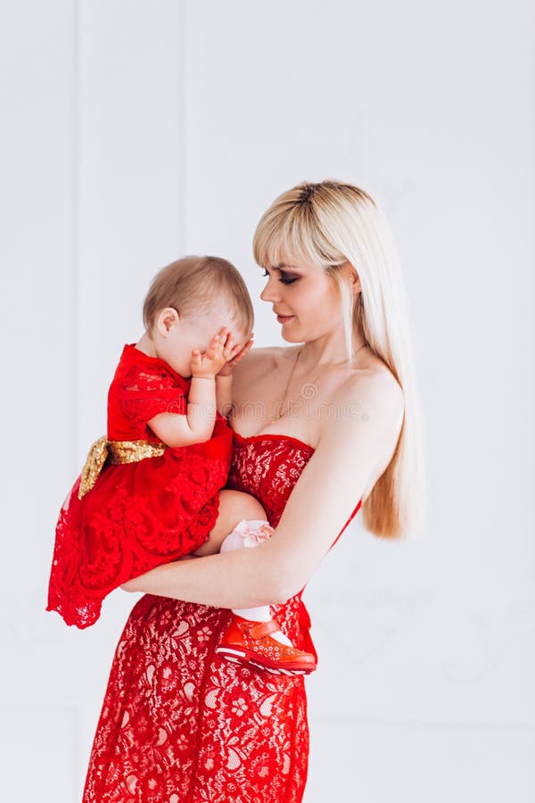 Gentil, famille, bonne photo de m?re et fille dans des robes rouges dans le studio Le jour et les filles de m?re photo stock Gentil, famille, bonne photo de m?re et fille dans des robes rouges dans le studio Le jour et les filles de m?re photo stock