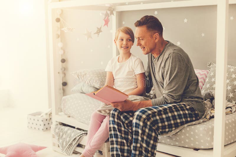 Gentil homme beau lisant un livre à sa fille image libre de droits Gentil homme beau lisant un livre à sa fille image libre de droits
