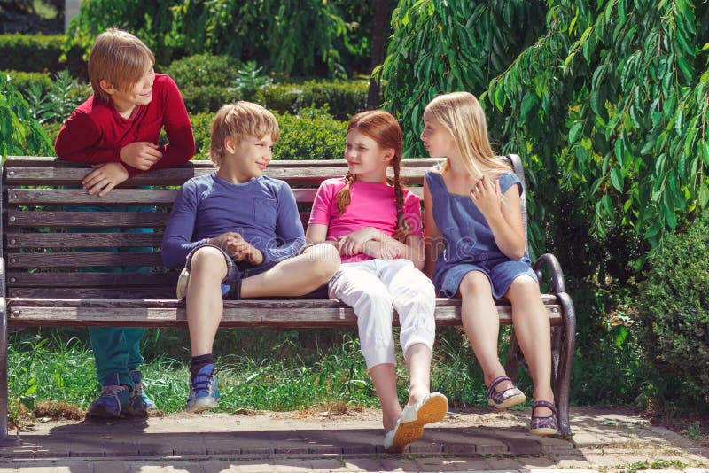 Gentils enfants de sourire s'asseyant sur le banc