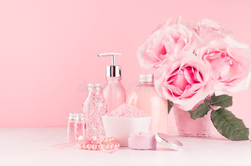 Gentle girlish dressing table with flowers, cosmetics products - rose oil, bath salt, cream, perfume, cotton towel, bottle and bow