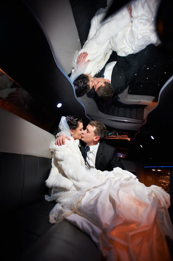 Gentle kiss bride and groom in wedding limo