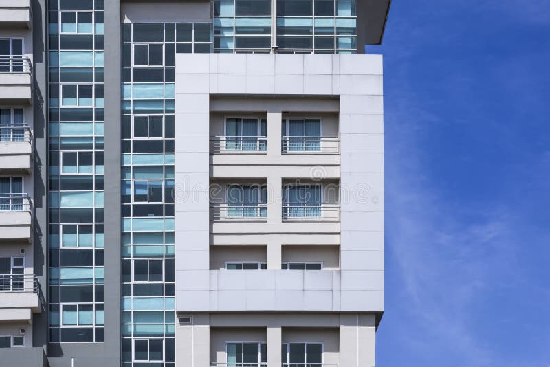 Glass windows and balcony on exterior view of modern high building with blue sky