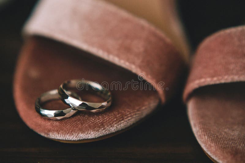 Geometrical original wedding rings from gold on the bride`s shoes from pink velvet. Close-up royalty free stock photography Geometrical original wedding rings from gold on the bride`s shoes from pink velvet. Close-up royalty free stock photography