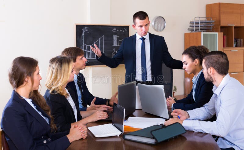 Gerente que discute sua equipe severamente durante fotografia de stock Gerente que discute sua equipe severamente durante fotografia de stock