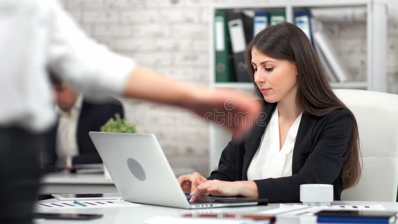 Gerichte jonge zakenvrouw die koffie of thee drinkt op het werk tijdens het werken met een laptop