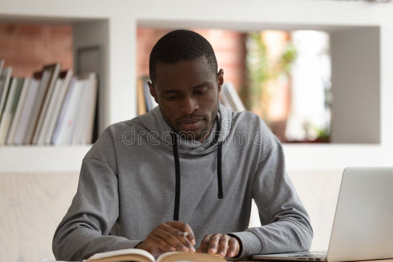 Focused male african american student preparing for final examination, reading textbook, writing down notes, essay or summary. Motivated concentrated young black guy studying, doing school project. Focused male african american student preparing for final examination, reading textbook, writing down notes, essay or summary. Motivated concentrated young black guy studying, doing school project.