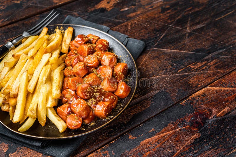 German currywurst meal, curry wurst with french fry served in a plate. Wooden background. Top view. Copy space