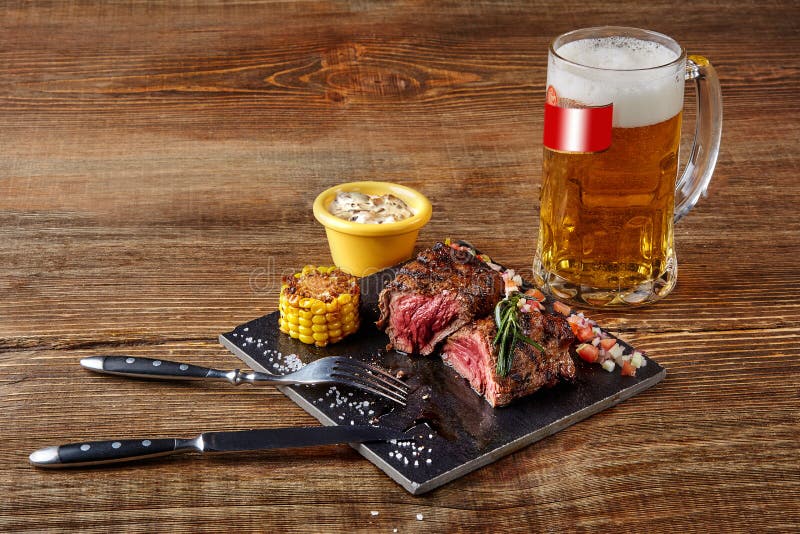 Geroosterd haasbiefstuklapje vlees roastbeef en paddestoelensaus op zwart scherp raad en glas bier op houten achtergrond royalty-vrije stock afbeeldingen Geroosterd haasbiefstuklapje vlees roastbeef en paddestoelensaus op zwart scherp raad en glas bier op houten achtergrond royalty-vrije stock afbeeldingen
