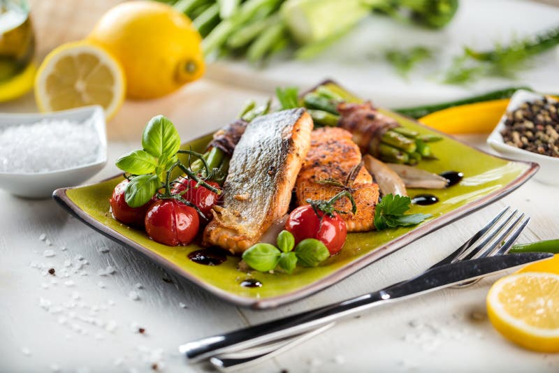 Geroosterde die zalm met groenten op groene steenplaat worden gediend op houten lijst royalty-vrije stock foto Geroosterde die zalm met groenten op groene steenplaat worden gediend op houten lijst royalty-vrije stock foto