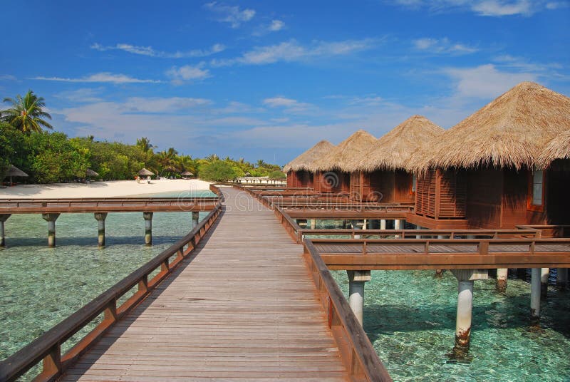 Geräumiger Overwater-Bungalow mit langem hölzernem Gehweg stockbilder
