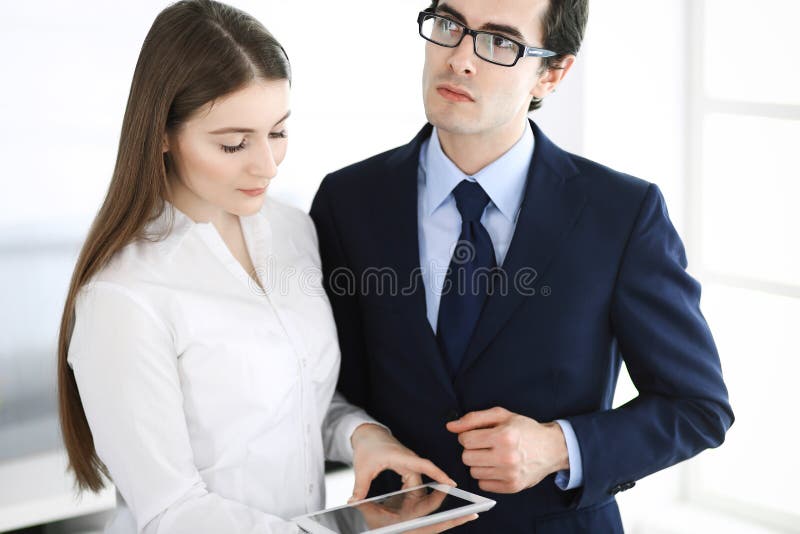 Businessmen and woman using tablet computer in modern office. Colleagues or company managers at workplace. Partners. Businessmen working with computer in modern office. Headshot of male entrepreneur or company manager at workplace. Partners discussing contract. Business concept.
