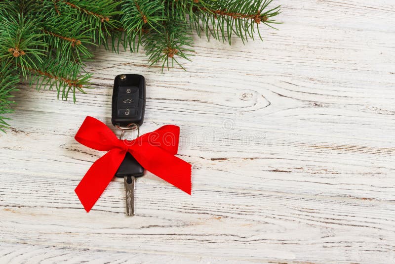 Geschenk für Weihnachtsautoschlüssel Großaufnahme von Autoschlüsseln mit rotem Bogen als Geschenk auf hölzernem Hintergrund