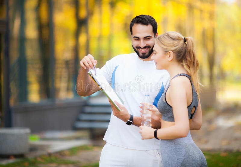 Geschiktheid Het persoonlijke de Vrouw van Trainertakes notes while Openlucht Uitoefenen stock fotografie Geschiktheid Het persoonlijke de Vrouw van Trainertakes notes while Openlucht Uitoefenen stock fotografie