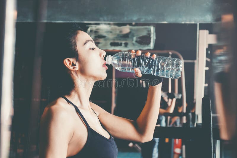 Geschiktheidsvrouw in het drinkwater van de zoldergymnastiek na een goede training stock afbeelding Geschiktheidsvrouw in het drinkwater van de zoldergymnastiek na een goede training stock afbeelding