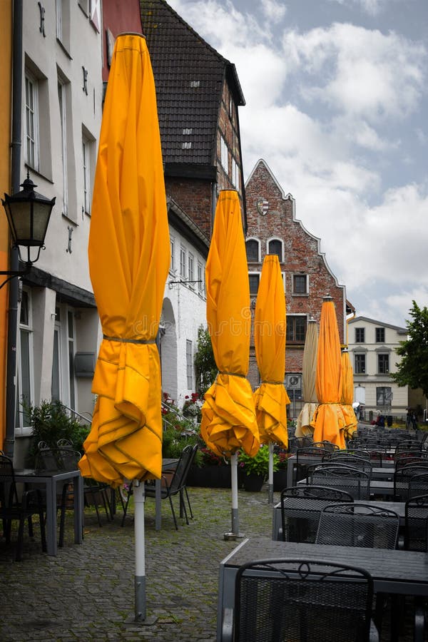 Geschlossene gelbe Sonnenschirme in einem Straßencafé auf einem regnerischen Sommer d stockbilder Geschlossene gelbe Sonnenschirme in einem Straßencafé auf einem regnerischen Sommer d stockbilder
