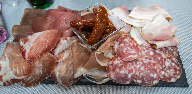 Geschnittener Mischitaliener: Salami, roher Schinken, Speck und trockene Tomaten stockbild Geschnittener Mischitaliener: Salami, roher Schinken, Speck und trockene Tomaten stockbild