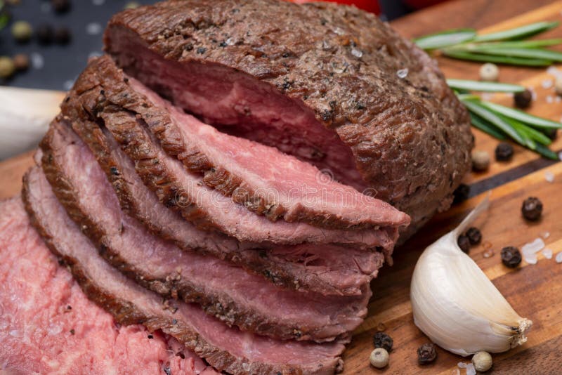 Geschnittenes bäuerisches saftiges Mais-Roastbeef geschmückt mit Tomaten, frischen Rosemary Herb-, Knoblauch-und Regenbogen-Pfeff stockfotos Geschnittenes bäuerisches saftiges Mais-Roastbeef geschmückt mit Tomaten, frischen Rosemary Herb-, Knoblauch-und Regenbogen-Pfeff stockfotos